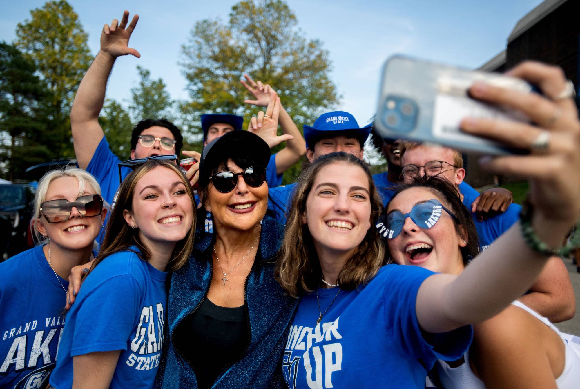 Students posing with President Mantella giving the "Anchor Up!" signal in preparation for a GVSU football game